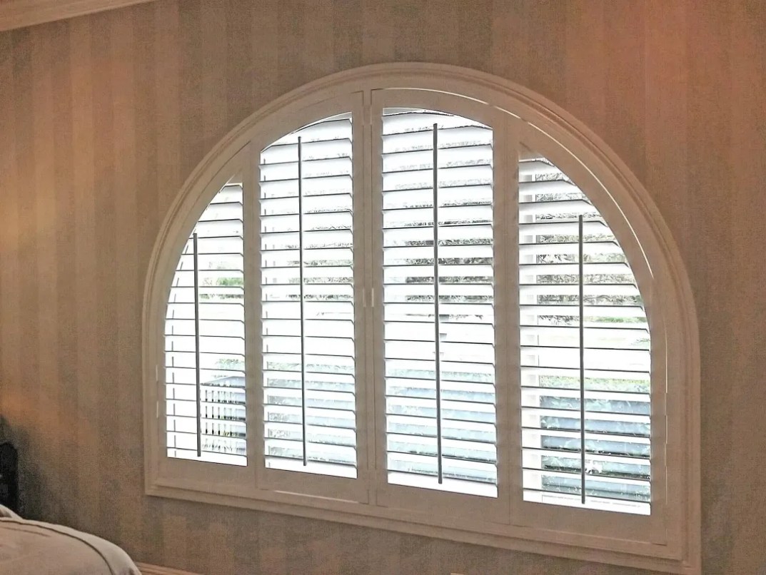 Arched window shutters installed in a Corona home, custom-fitted to follow the curved window design