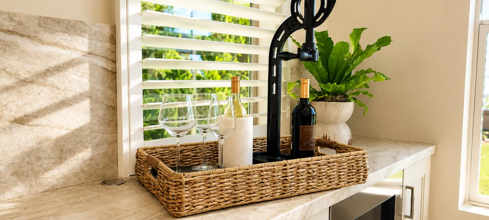 White plantation shutters above a wet bar with stone backsplash