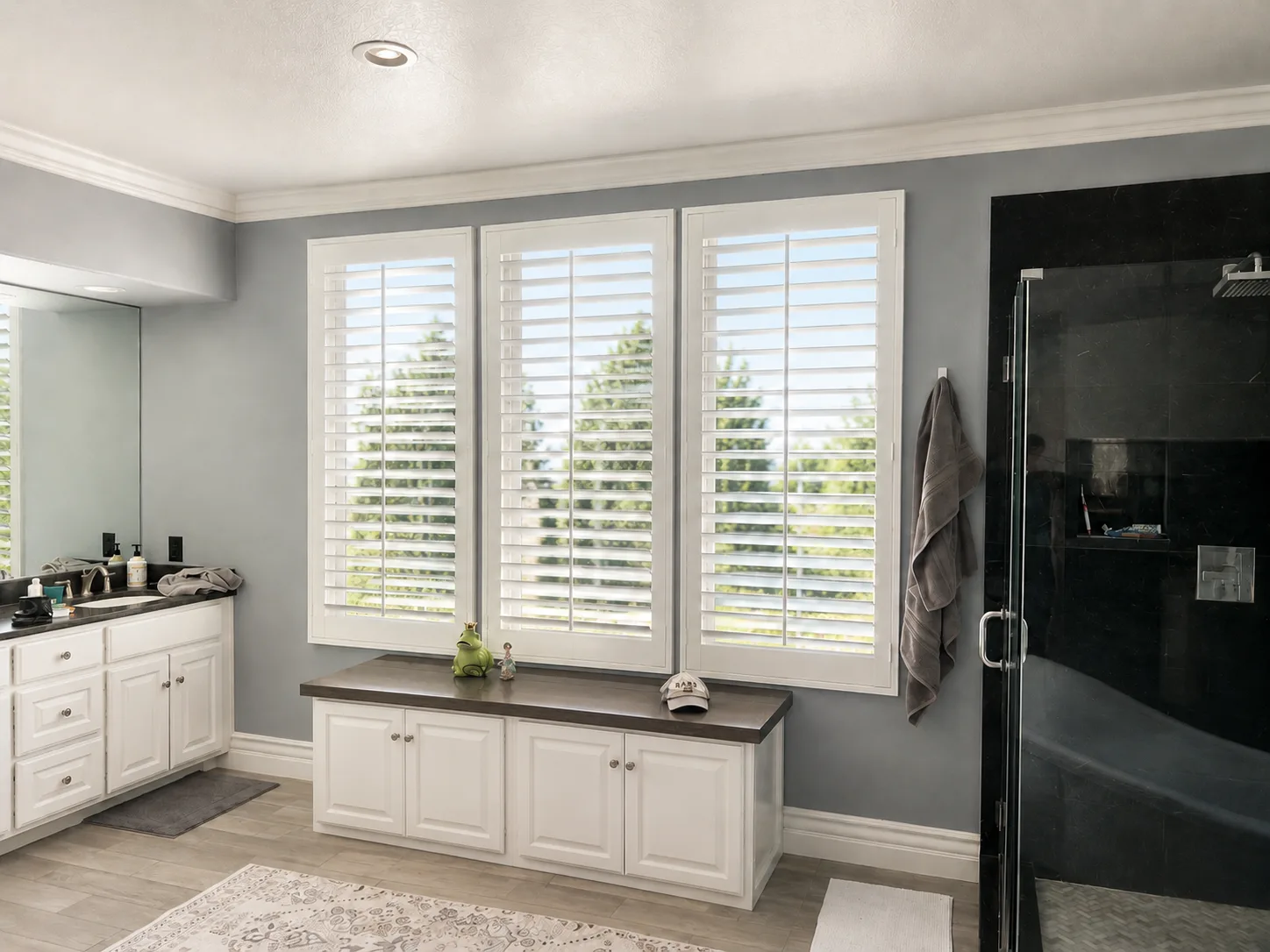 White plantation shutters across three master bath windows
