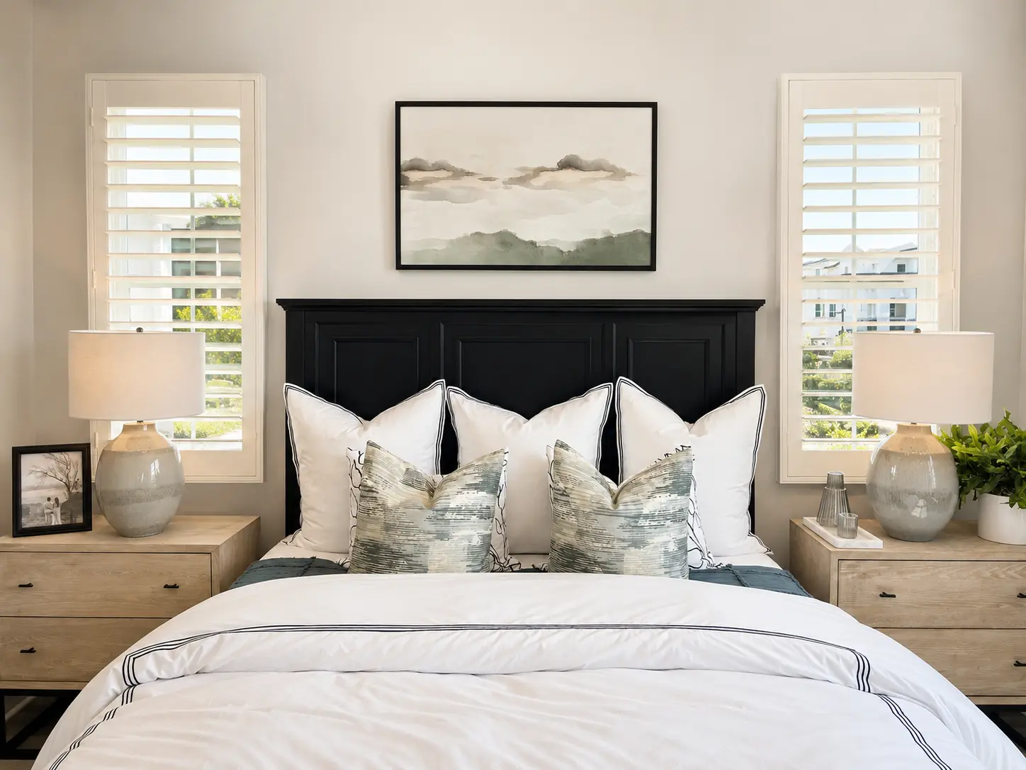 Cream plantation shutters flanking a black headboard in a primary bedroom