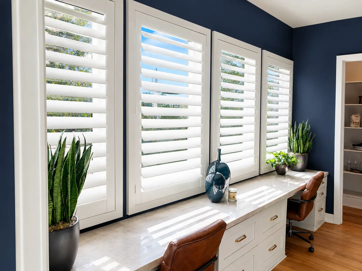White plantation shutters across a navy-walled home office desk