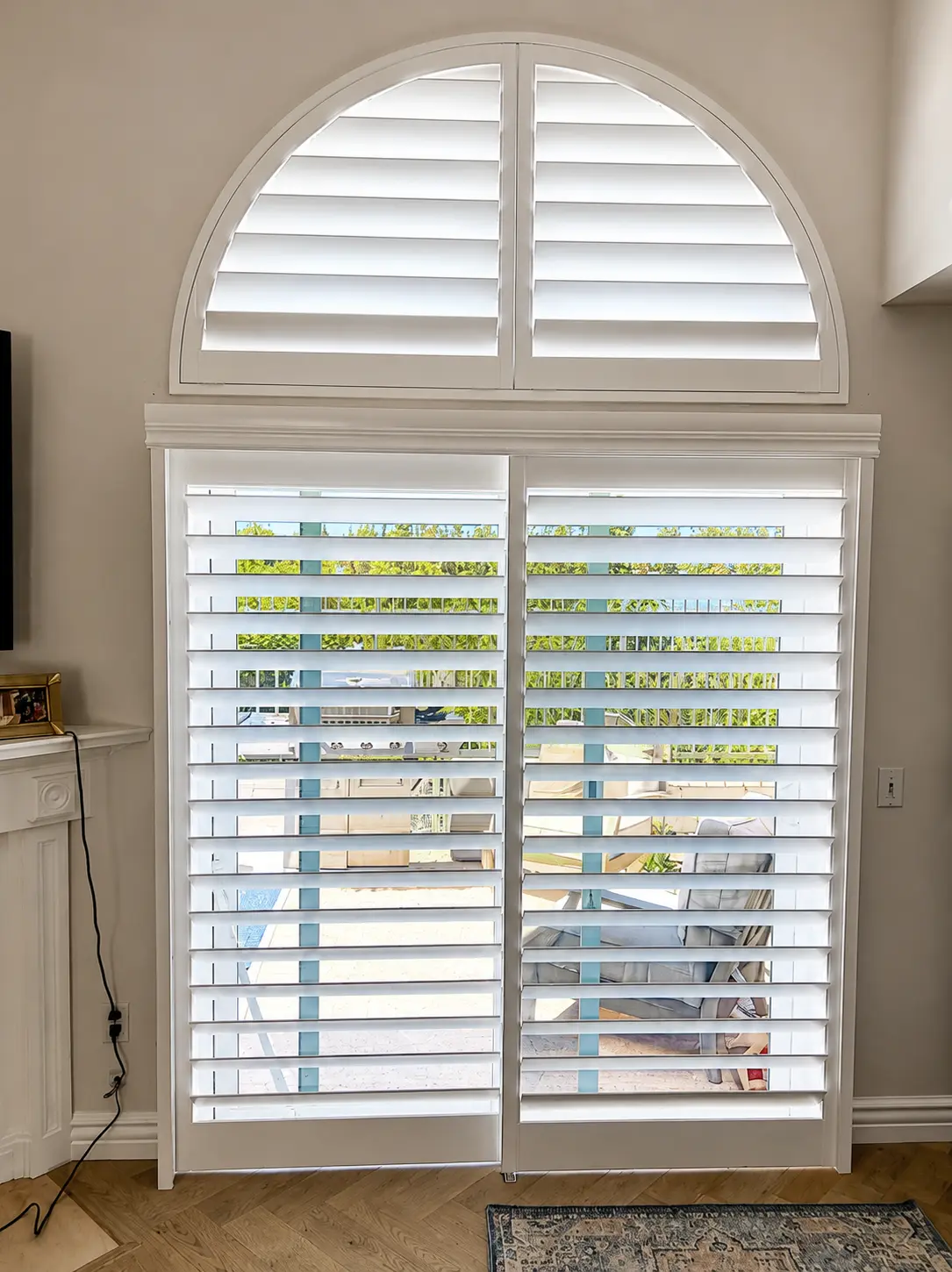 White plantation shutters with arch-top transom on a tall living room window