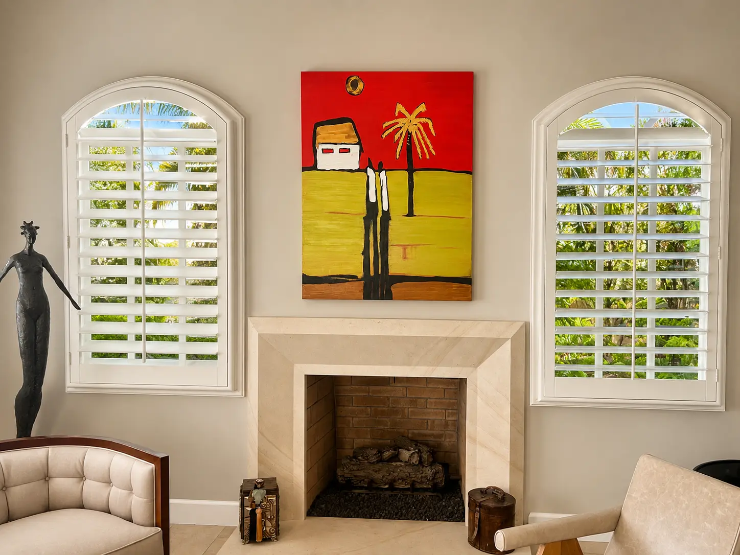 White plantation shutters on two tall arched-top windows flanking a fireplace