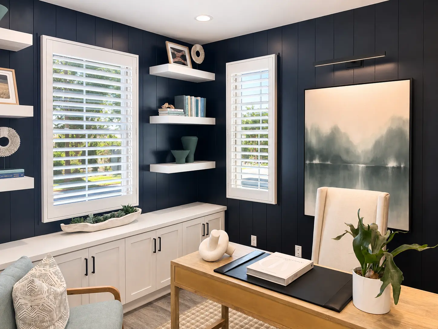 White plantation shutters in a navy-paneled home office