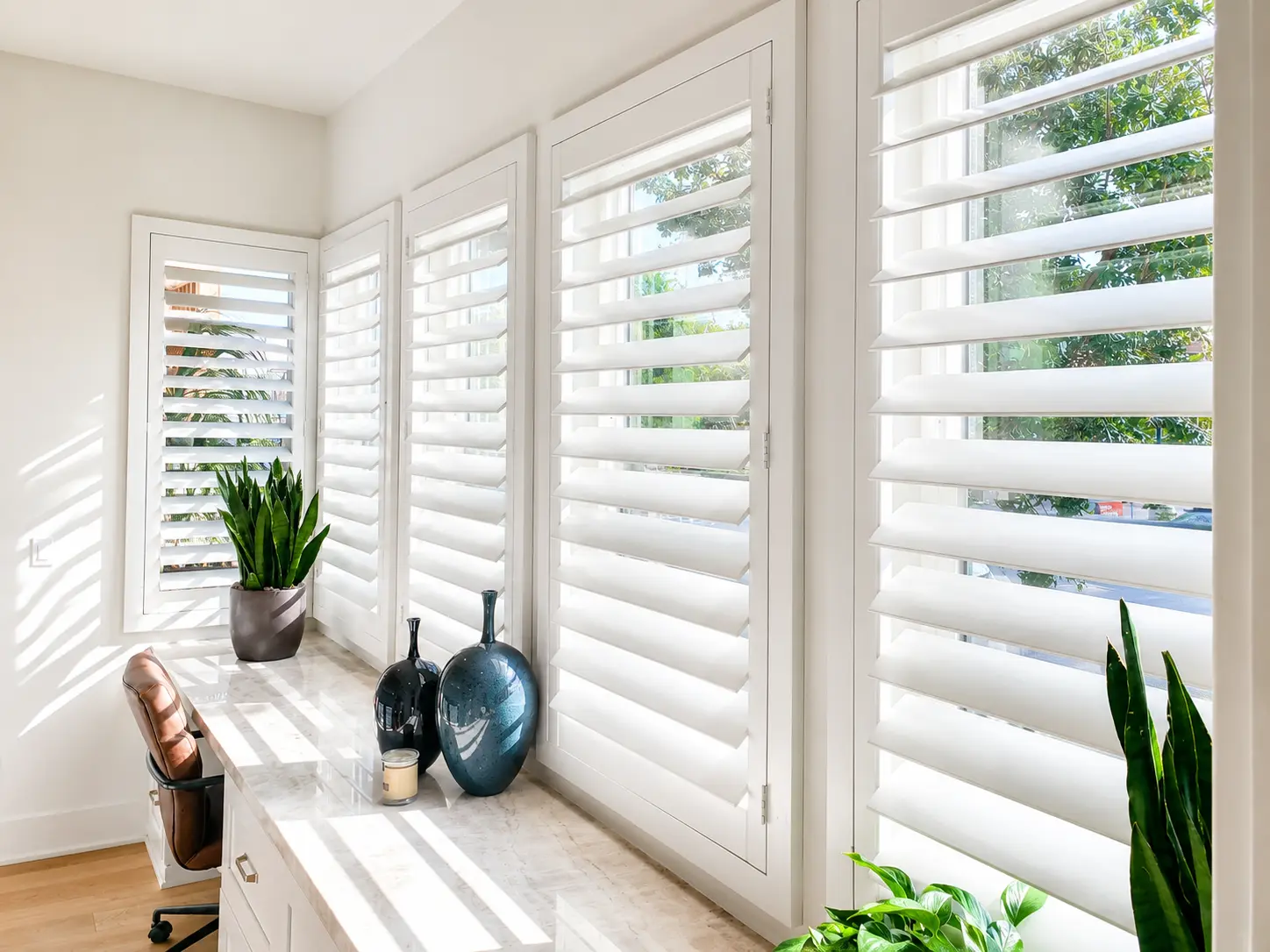 White plantation shutters wrapping a corner of a home office