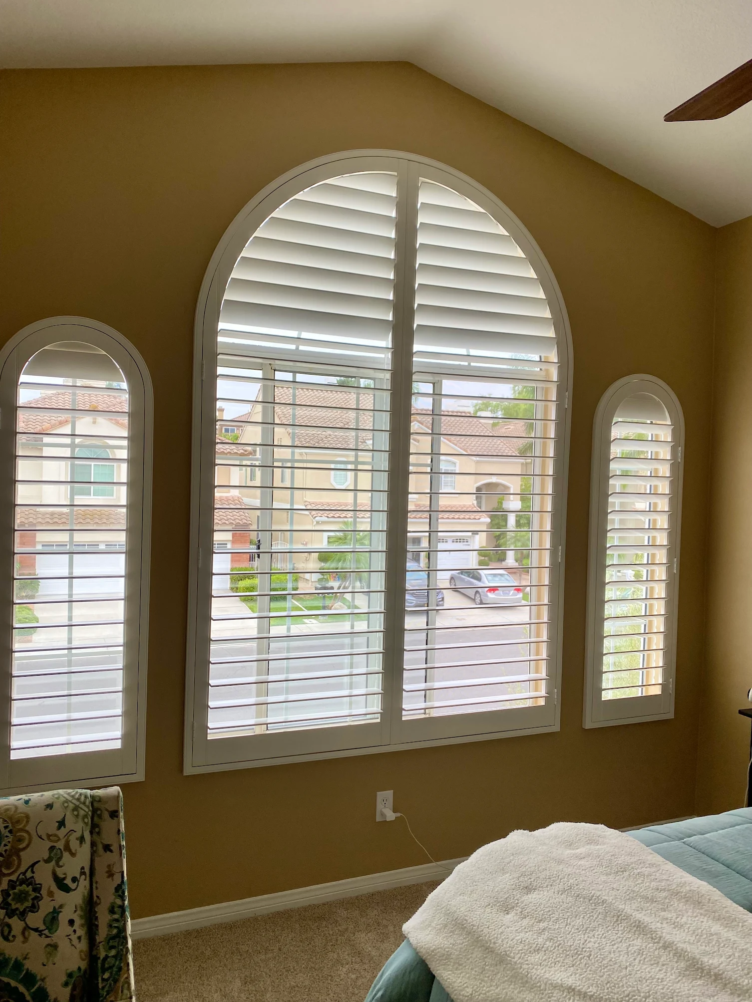 Arched bedroom window with custom plantation shutter and matching side panels